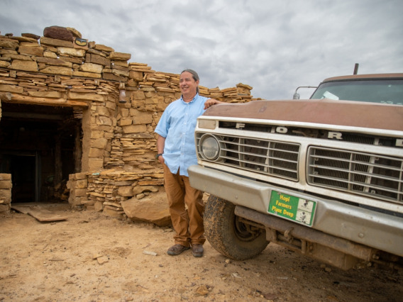 Michael Kotutwa Johnson stands next to his vintage Ford truck outside of the home he built by hand on Hopi land. 