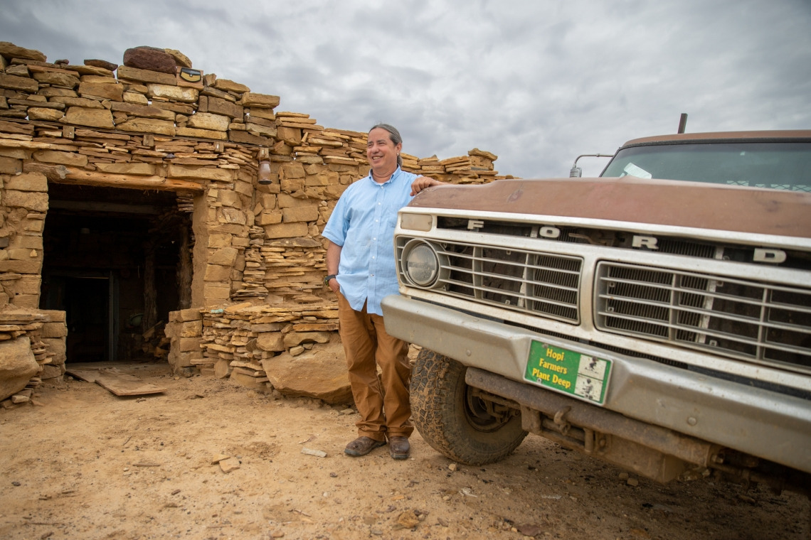 Michael Kotutwa Johnson stands next to his vintage Ford truck outside of the home he built by hand on Hopi land. 